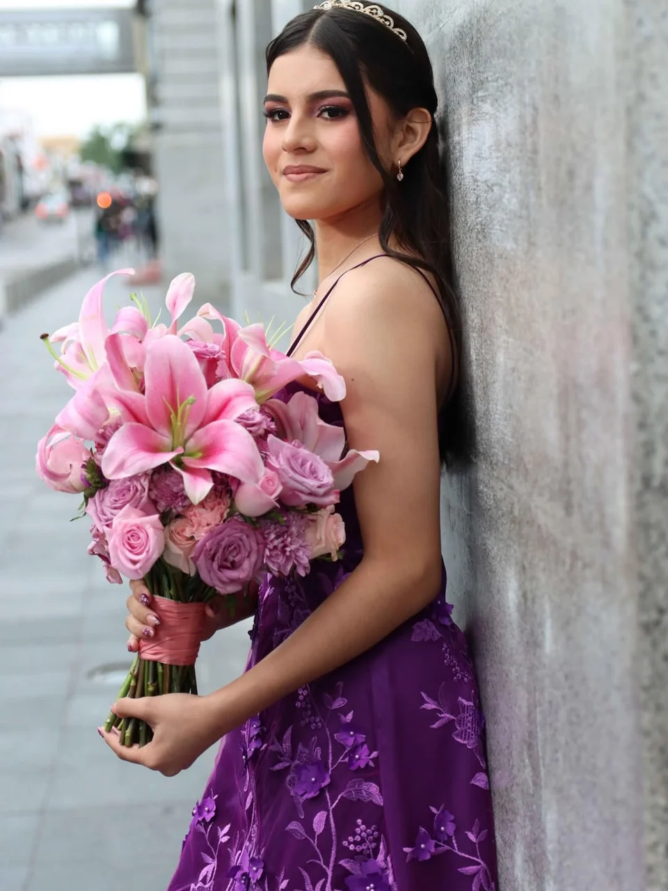 Detalle del peinado y maquillaje de quinceañera con ramo rosa