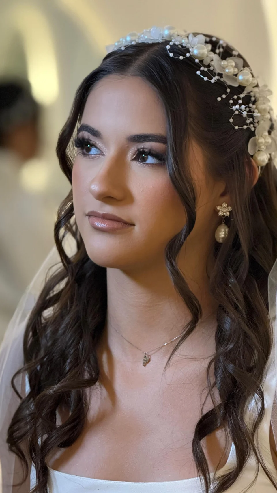 Novia con maquillaje luminoso, peinado con rizos y tocado floral
