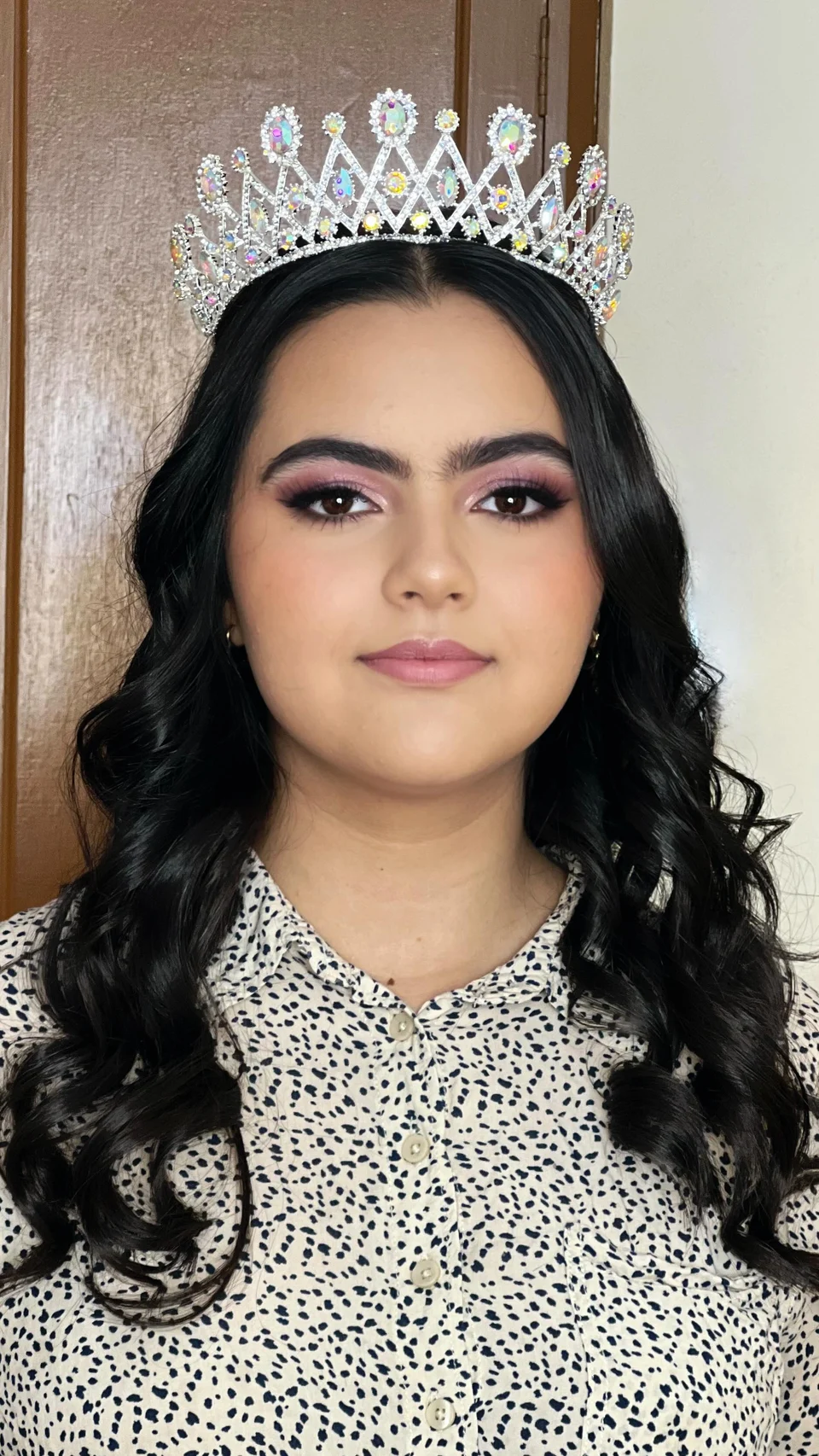 Quinceañera con maquillaje en tonos rosa, cabello con ondas y tiara